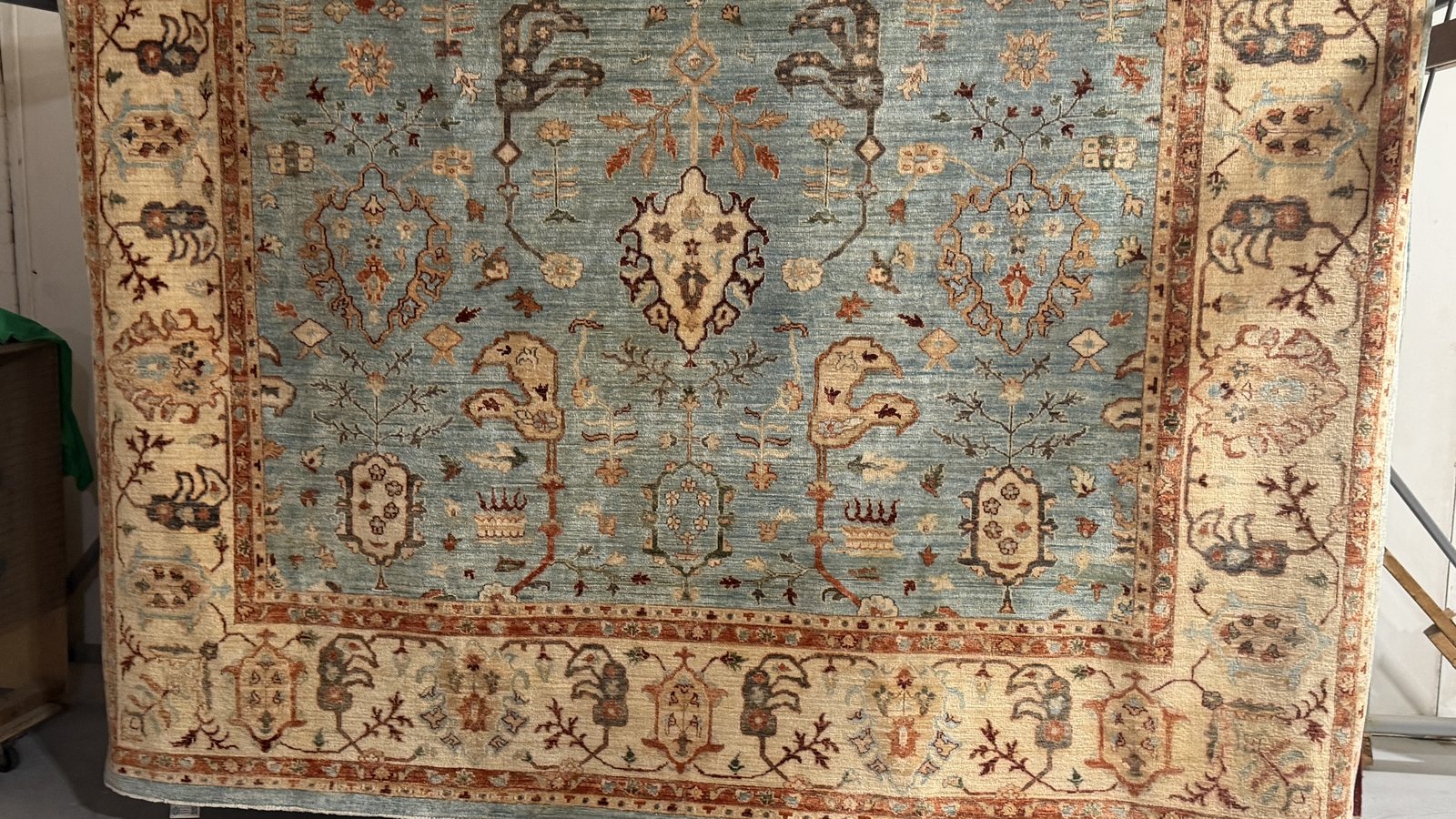 A wool rug on the rack, rinse water still running clear off the pile
