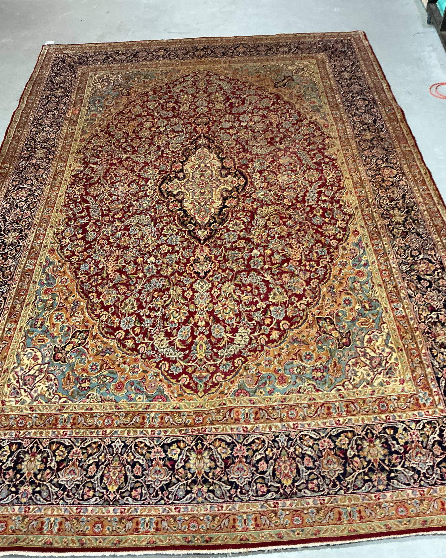 The same rug after cleaning, with the red field, gold corner spandrels and blue-green florals showing clearly