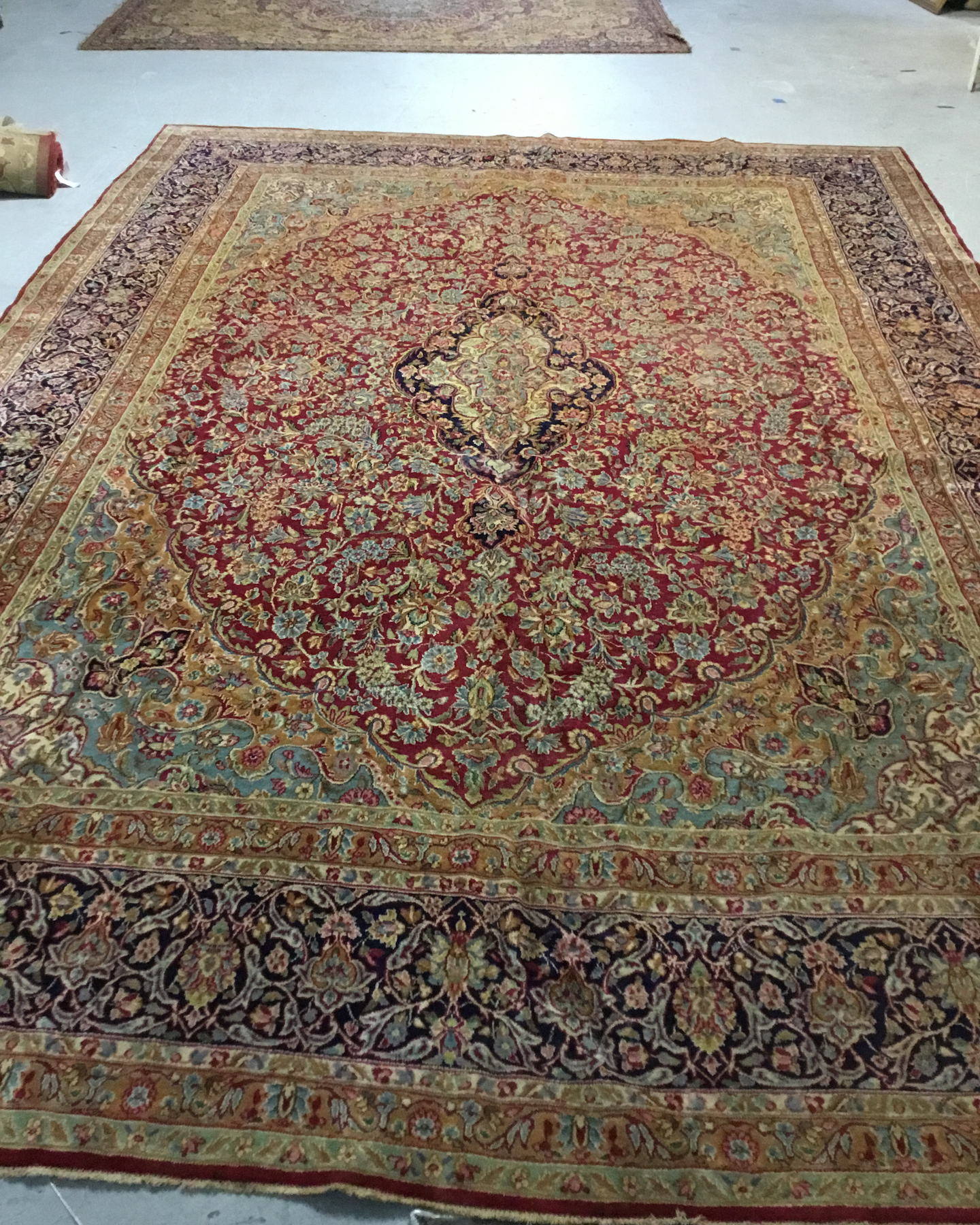 Hand-knotted Persian rug before cleaning, the deep red field and blue-green floral tracery muted and greyed