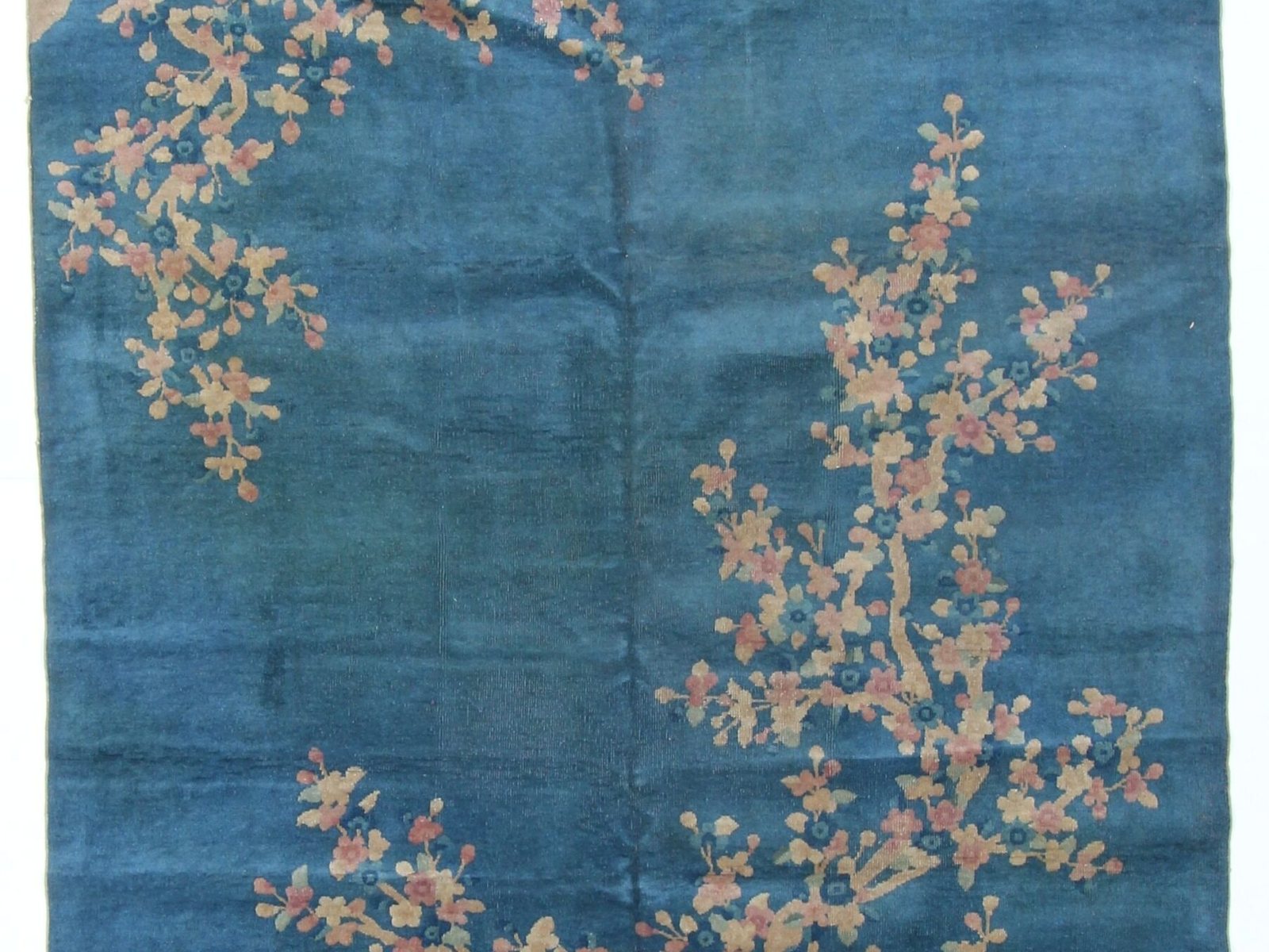 Chinese rug detail showing carved relief around a floral motif on an open field