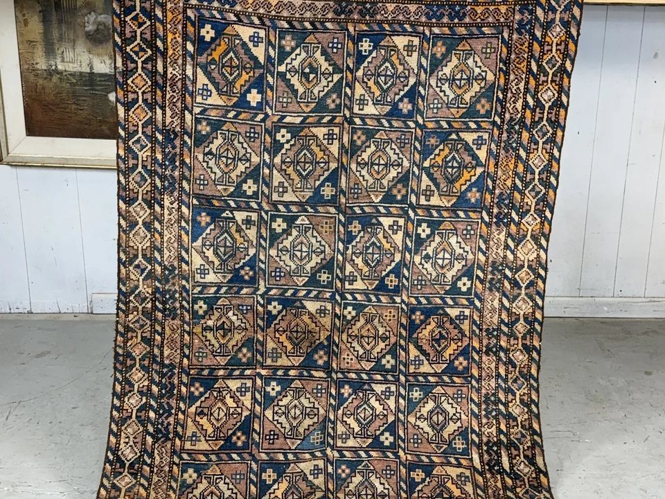 Hand-knotted oriental rug photographed flat, showing a bordered field and repeating motifs